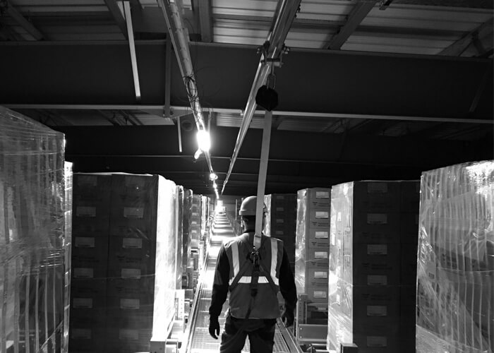 Man using an Overhead Fall Arrest Track in warehouse