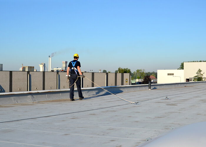 Man Working at Height on a Flat Roof Attached to a Safety Line
